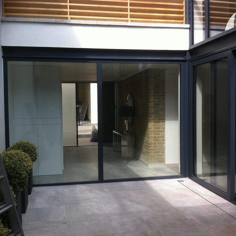 Floor-to-ceiling sliding doors opening to courtyard in Esher